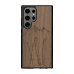 Coque de protection en bois véritable fabriquée en France pour Samsung S25 Ultra sur le thème de la montagne, du ski et de la neige avec un motif représentant une paire de ski plantée dans la neige avec en fond des montagnes enneigées
