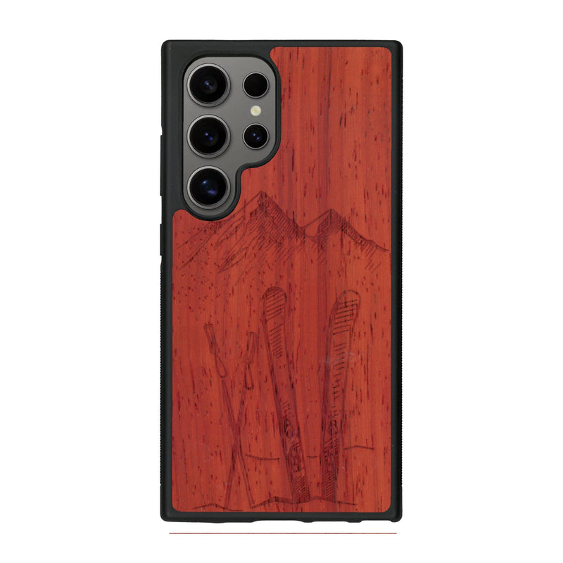 Coque de protection en bois véritable fabriquée en France pour Samsung S25 Ultra sur le thème de la montagne, du ski et de la neige avec un motif représentant une paire de ski plantée dans la neige avec en fond des montagnes enneigées