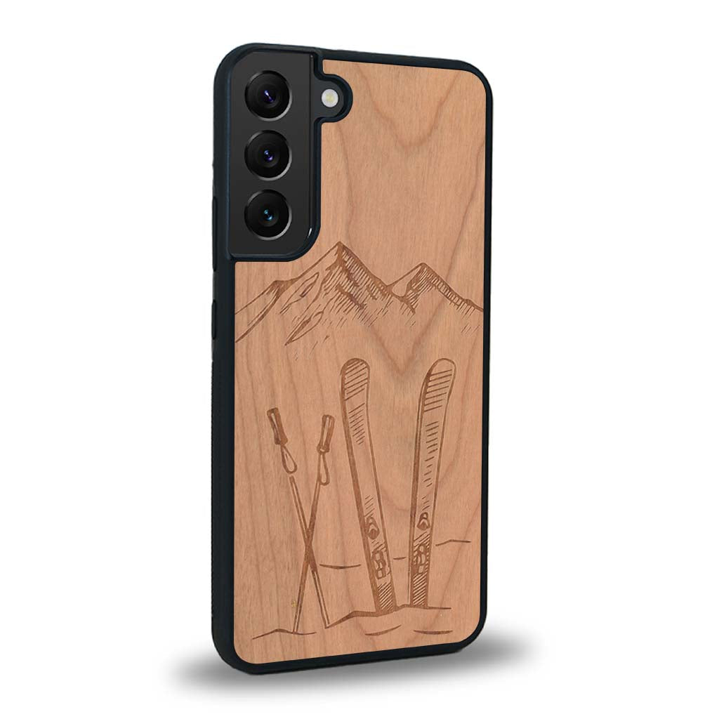 Coque de protection en bois véritable fabriquée en France pour Samsung S25FE sur le thème de la montagne, du ski et de la neige avec un motif représentant une paire de ski plantée dans la neige avec en fond des montagnes enneigées