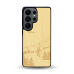 Coque de protection en bois véritable fabriquée en France pour Samsung S26 Ultra sur le thème de la montagne, du ski et de la neige avec un motif représentant une paire de ski plantée dans la neige avec en fond des montagnes enneigées