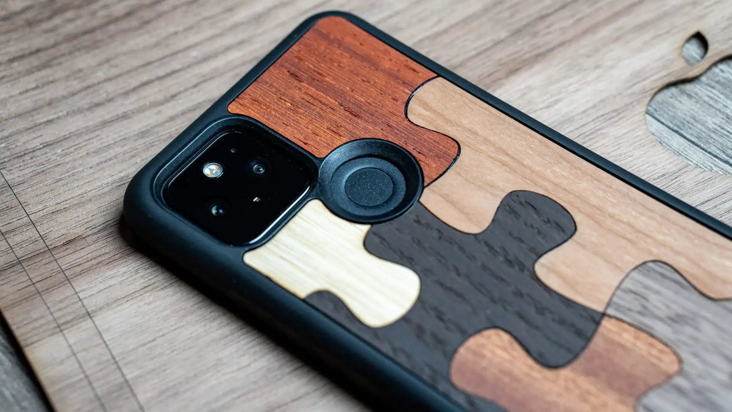 Un téléphone sur un bureau avec une coque en bois, modèle Puzzle.