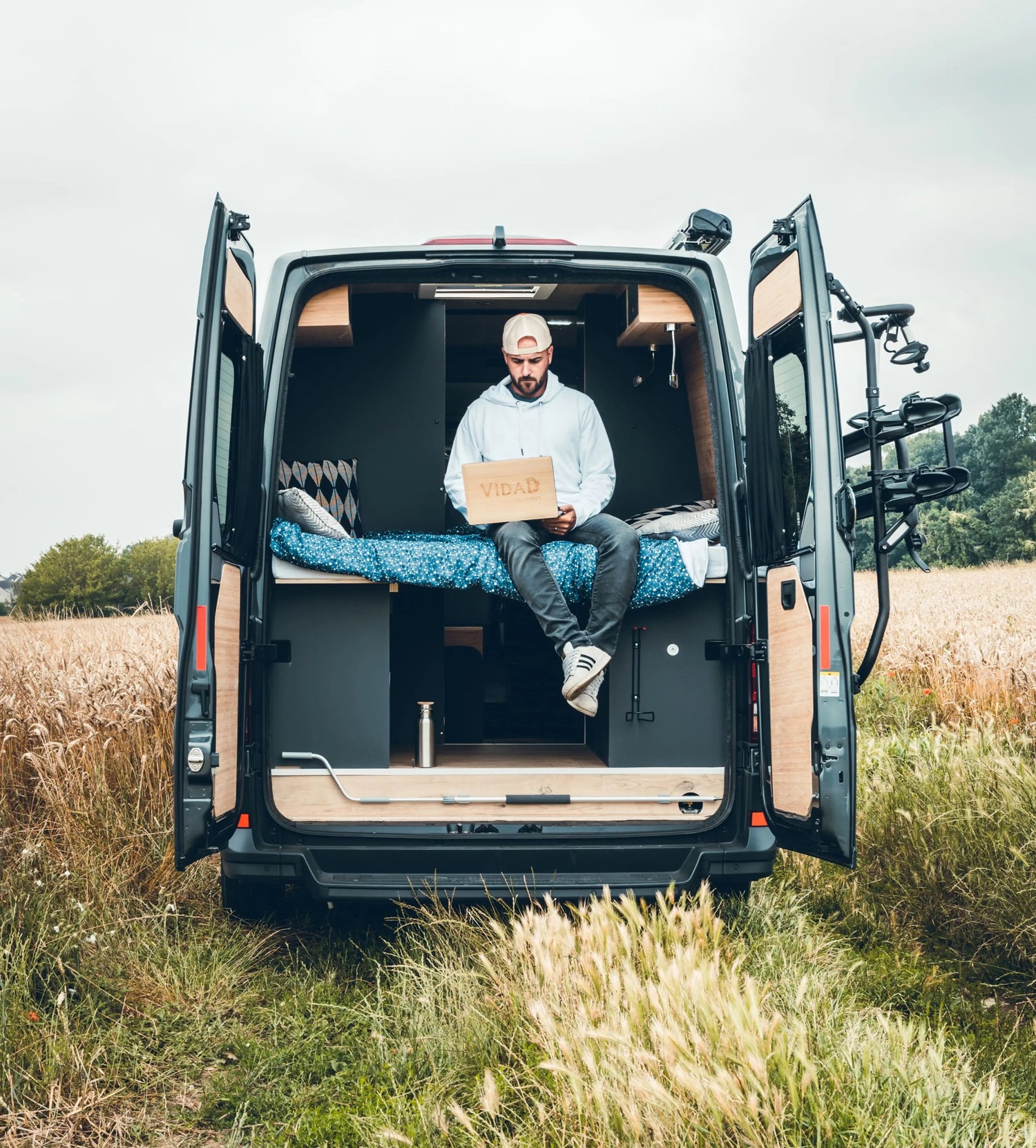 Un homme dans un camion qui travaille sur un ordinateur portable MacBook avec une coque en bois pour ordinateur portable personnalisée, fabrication française et artisanale.