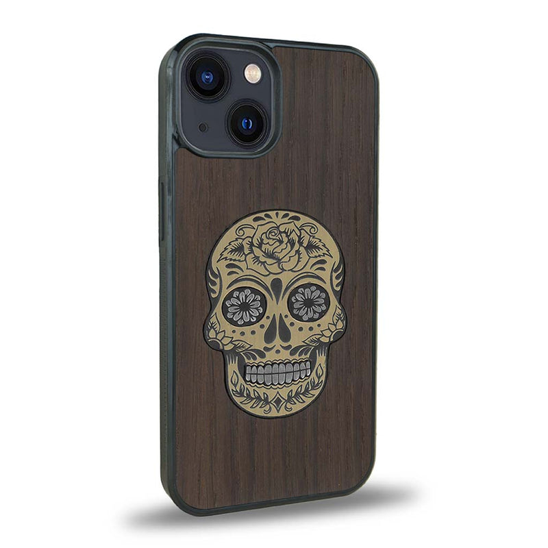 Coque de protection en bois véritable fabriquée en France pour iPhone 15 alliant du chêne fumé avec du métal argenté et doré représentant une tête de mort mexicaine sur le thème Dia de los Muertos