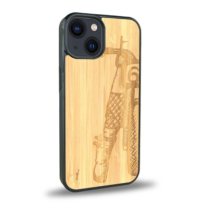 Coque de protection en bois véritable fabriquée en France pour iPhone 15 représentant une vue de face d'une femme sur une moto vintage dessinée à la main par l'artiste Maud Dabs