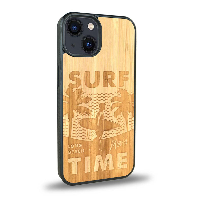 Coque de protection en bois véritable fabriquée en France pour iPhone 15 Plus sur le thème chill avec un motif représentant une silouhette tenant une planche de surf sur une plage entouré de palmiers et les mots "Surf Time Long Beach Miami"