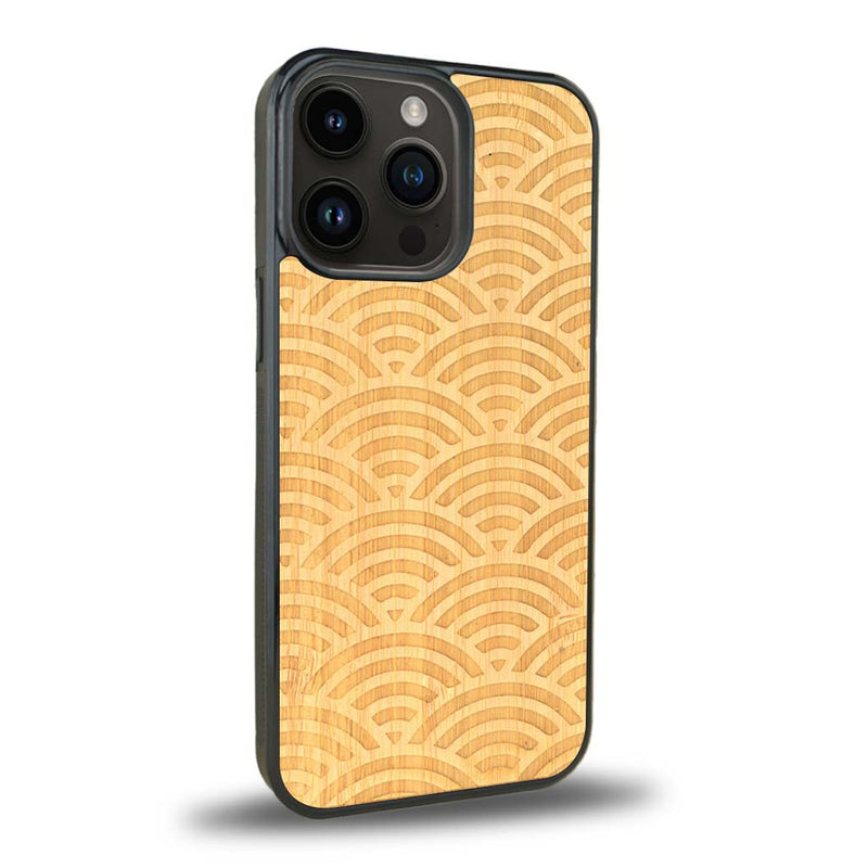 Coque de protection en bois véritable fabriquée en France pour iPhone 15 Pro baptisée "La Sinjak" avec un motif de gravure abstrait représentant la répétition d'un symbole wifi