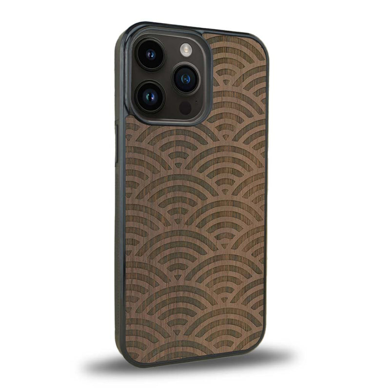 Coque de protection en bois véritable fabriquée en France pour iPhone 15 Pro baptisée "La Sinjak" avec un motif de gravure abstrait représentant la répétition d'un symbole wifi