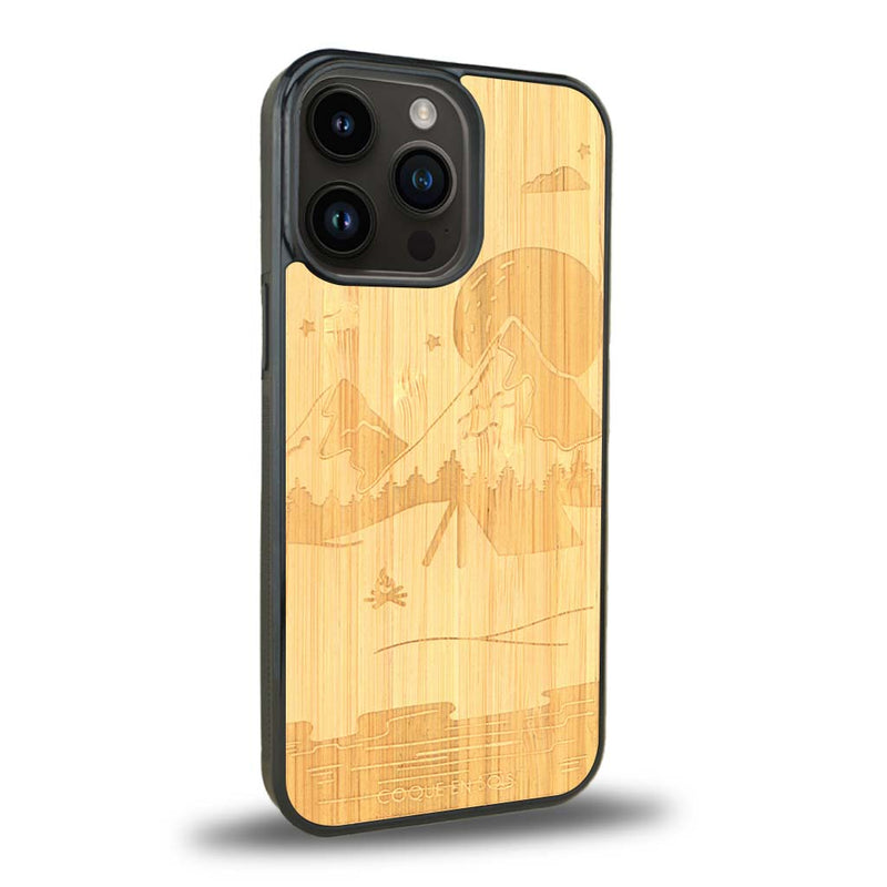 Coque de protection en bois véritable fabriquée en France pour iPhone 15 Pro sur le thème du camping en pleine nature représentant une tente avec un feu de camp entouré de montagnes