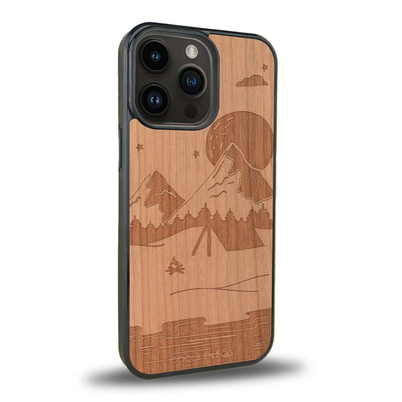 Coque de protection en bois véritable fabriquée en France pour iPhone 15 Pro sur le thème du camping en pleine nature représentant une tente avec un feu de camp entouré de montagnes