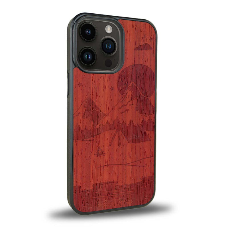 Coque de protection en bois véritable fabriquée en France pour iPhone 15 Pro sur le thème du camping en pleine nature représentant une tente avec un feu de camp entouré de montagnes