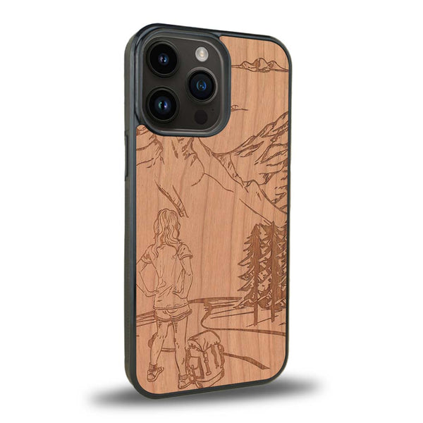 Coque de protection en bois véritable fabriquée en France pour iPhone 15 Pro sur le thème de la randonnée en montagne et de l'aventure avec une gravure représentant une femme de dos face à un paysage de nature