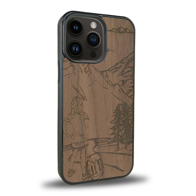 Coque de protection en bois véritable fabriquée en France pour iPhone 15 Pro sur le thème de la randonnée en montagne et de l'aventure avec une gravure représentant une femme de dos face à un paysage de nature