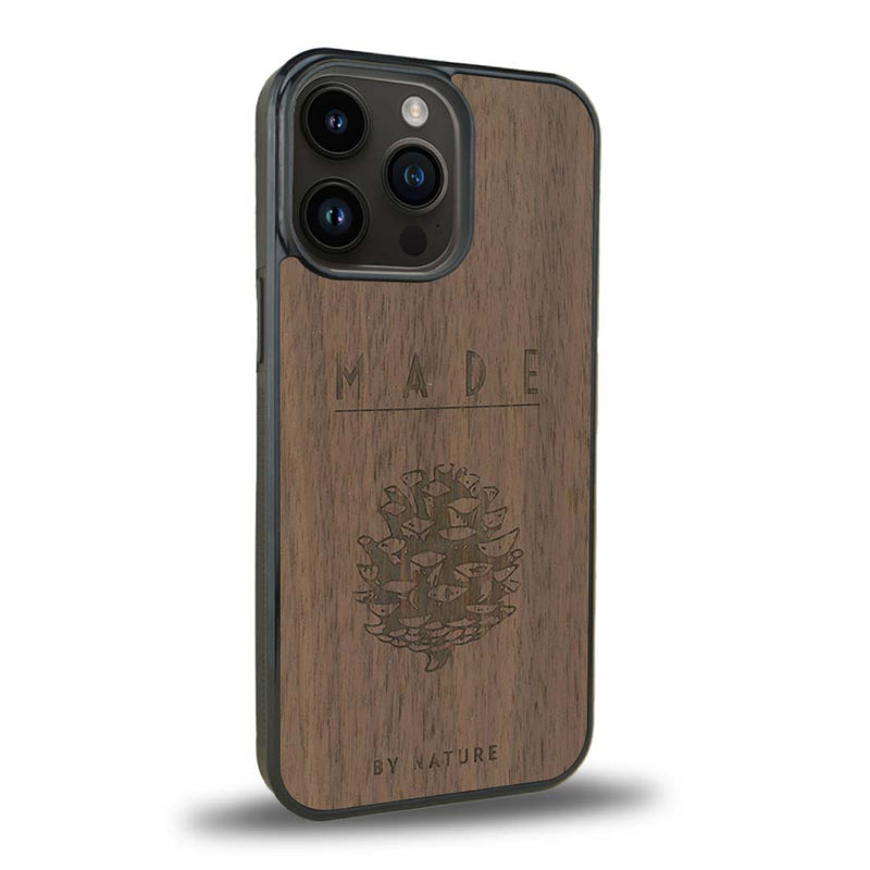 Coque de protection en bois véritable fabriquée en France pour iPhone 15 Pro sur le thème de la nature et des arbres avec une gravure représentant une pomme de pin et la phrase "made by nature"