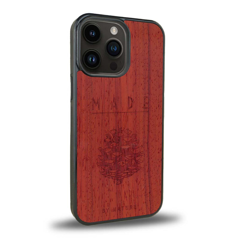 Coque de protection en bois véritable fabriquée en France pour iPhone 15 Pro sur le thème de la nature et des arbres avec une gravure représentant une pomme de pin et la phrase "made by nature"