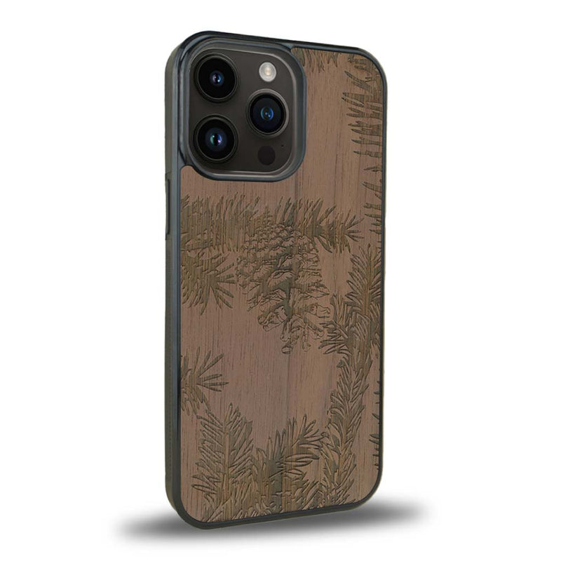 Coque de protection en bois véritable fabriquée en France pour iPhone 15 Pro Max sur le thème de la nature des arbres avec un motif de gravure représentant des épines de sapin et des pommes de pin