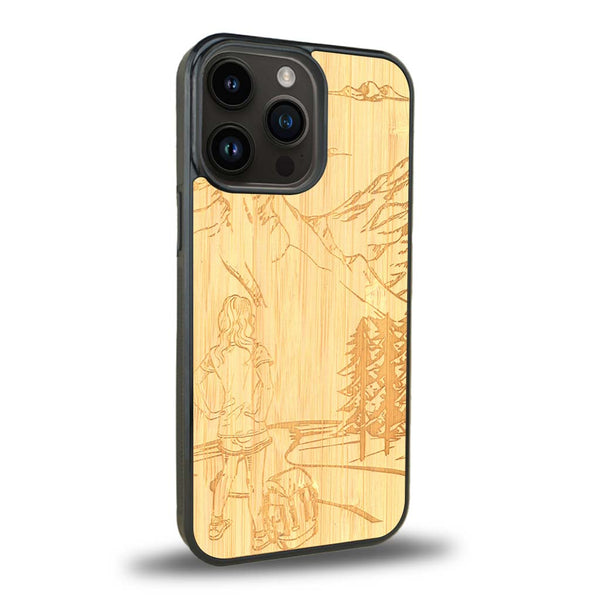 Coque de protection en bois véritable fabriquée en France pour iPhone 15 Pro Max sur le thème de la randonnée en montagne et de l'aventure avec une gravure représentant une femme de dos face à un paysage de nature