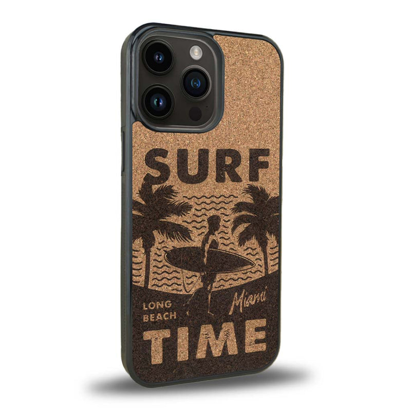 Coque de protection en bois véritable fabriquée en France pour iPhone 15 Pro Max sur le thème chill avec un motif représentant une silouhette tenant une planche de surf sur une plage entouré de palmiers et les mots "Surf Time Long Beach Miami"
