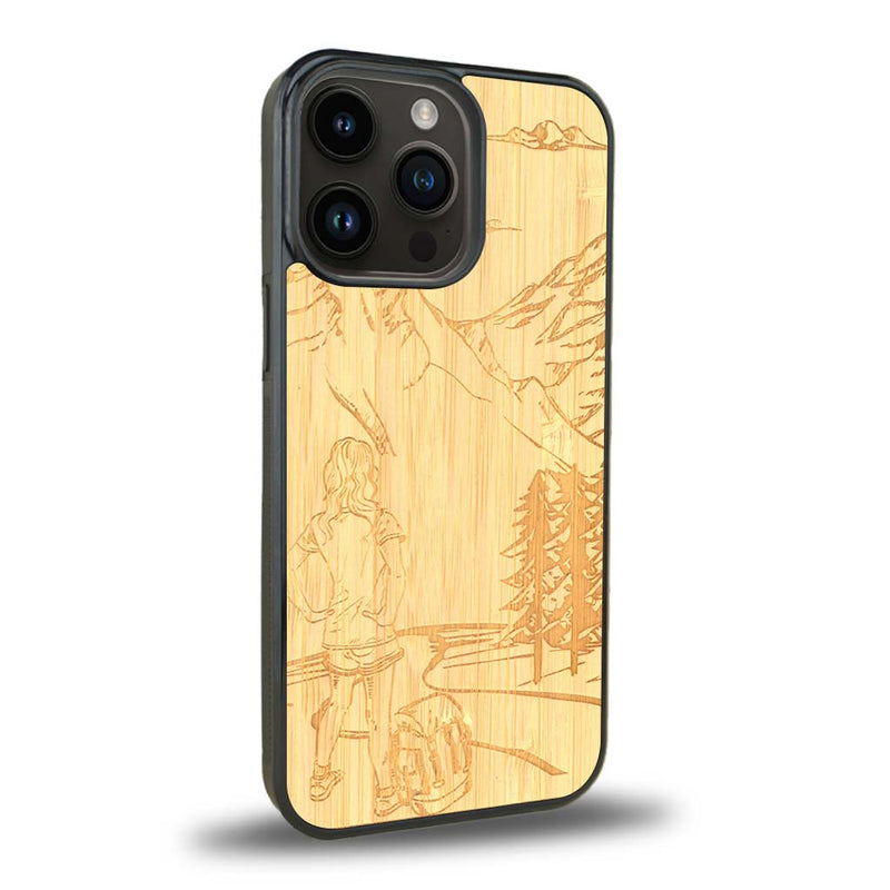 Coque de protection en bois véritable fabriquée en France pour iPhone 15 Pro + MagSafe® sur le thème de la randonnée en montagne et de l'aventure avec une gravure représentant une femme de dos face à un paysage de nature