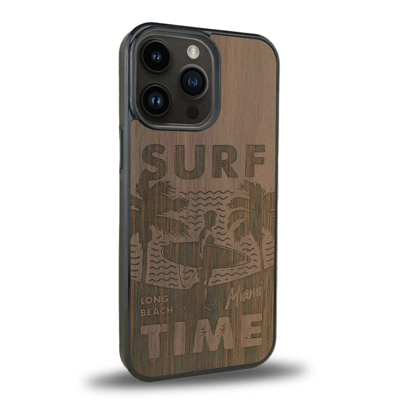 Coque de protection en bois véritable fabriquée en France pour iPhone 15 Pro sur le thème chill avec un motif représentant une silouhette tenant une planche de surf sur une plage entouré de palmiers et les mots "Surf Time Long Beach Miami"