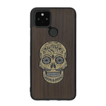 Coque de protection en bois véritable fabriquée en France pour Google Pixel 4a 5g alliant du chêne fumé avec du métal argenté et doré représentant une tête de mort mexicaine sur le thème Dia de los Muertos