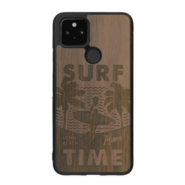Coque de protection en bois véritable fabriquée en France pour Google Pixel 4a 5g sur le thème chill avec un motif représentant une silouhette tenant une planche de surf sur une plage entouré de palmiers et les mots "Surf Time Long Beach Miami"