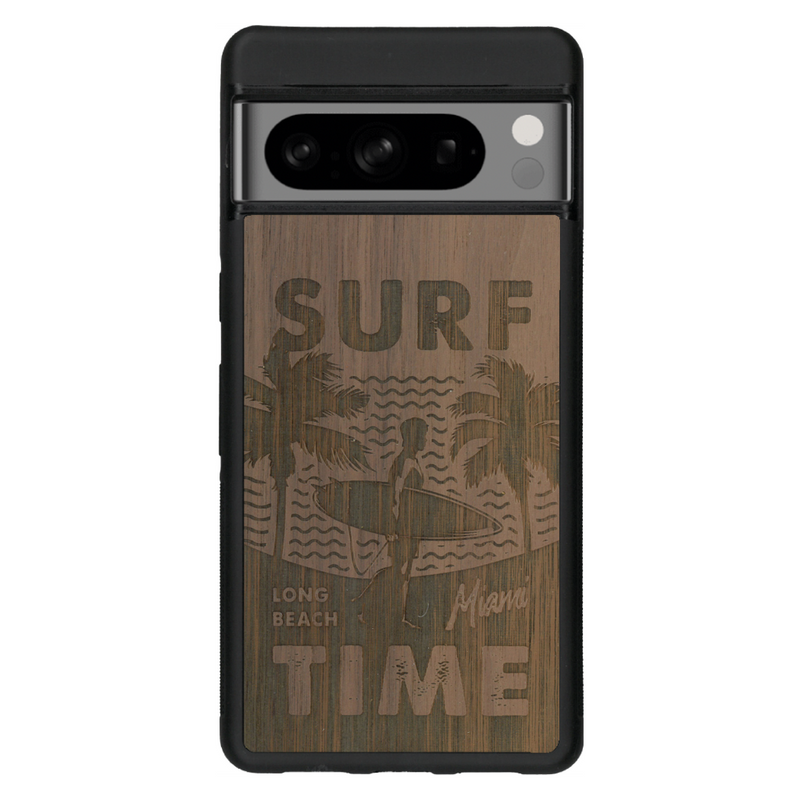 Coque de protection en bois véritable fabriquée en France pour Google Pixel 6 sur le thème chill avec un motif représentant une silouhette tenant une planche de surf sur une plage entouré de palmiers et les mots "Surf Time Long Beach Miami"