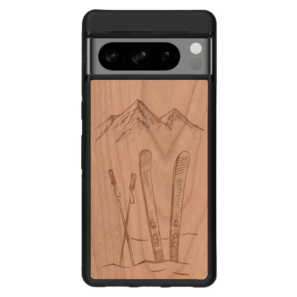 Coque de protection en bois véritable fabriquée en France pour Google Pixel 6 sur le thème de la montagne, du ski et de la neige avec un motif représentant une paire de ski plantée dans la neige avec en fond des montagnes enneigées