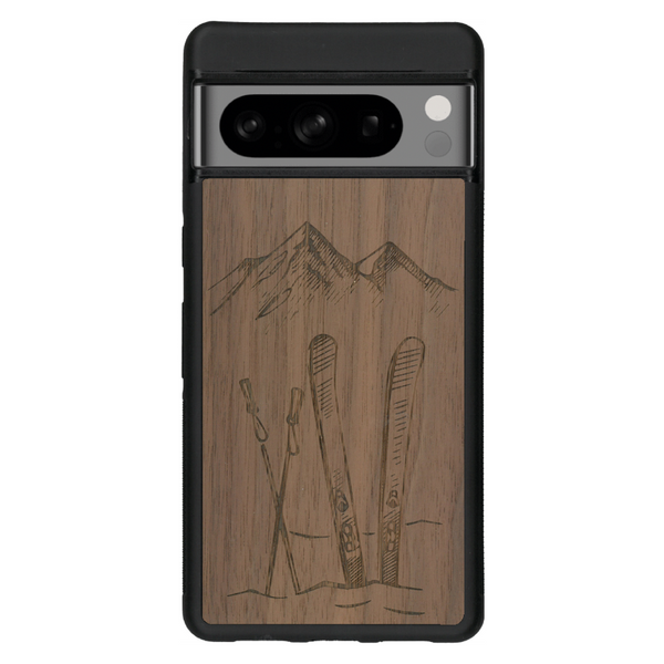 Coque de protection en bois véritable fabriquée en France pour Google Pixel 6 sur le thème de la montagne, du ski et de la neige avec un motif représentant une paire de ski plantée dans la neige avec en fond des montagnes enneigées