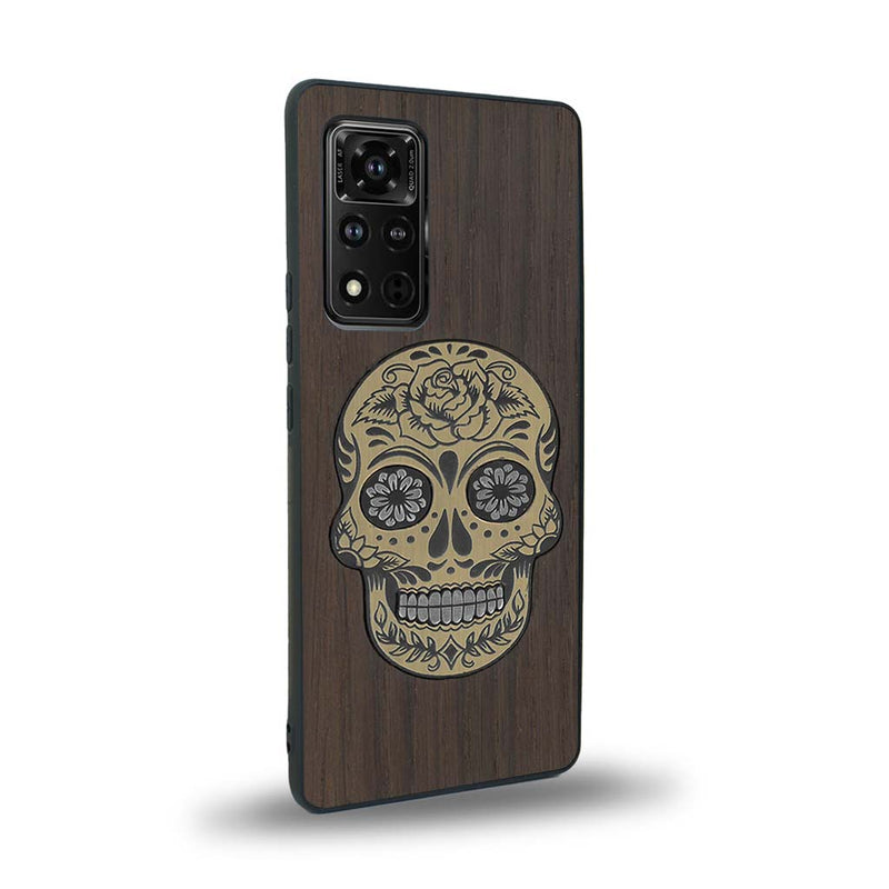 Coque de protection en bois véritable fabriquée en France pour Honor V40 alliant du chêne fumé avec du métal argenté et doré représentant une tête de mort mexicaine sur le thème Dia de los Muertos