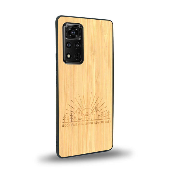 Coque de protection en bois véritable fabriquée en France pour Honor V40 sur le thème chill et nature avec un motif représentant un levé de soleil sur un paysage de montagne avec des sapins et un chalet et la phrase "Good friends, good adventure"