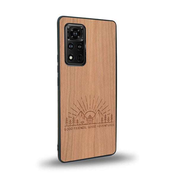 Coque de protection en bois véritable fabriquée en France pour Honor V40 sur le thème chill et nature avec un motif représentant un levé de soleil sur un paysage de montagne avec des sapins et un chalet et la phrase "Good friends, good adventure"