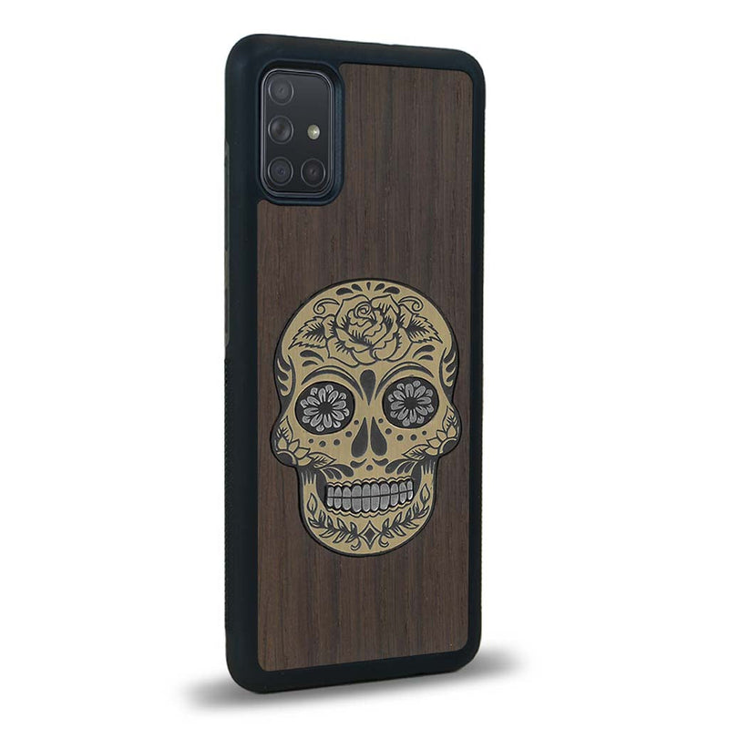 Coque de protection en bois véritable fabriquée en France pour Samsung A02S alliant du chêne fumé avec du métal argenté et doré représentant une tête de mort mexicaine sur le thème Dia de los Muertos