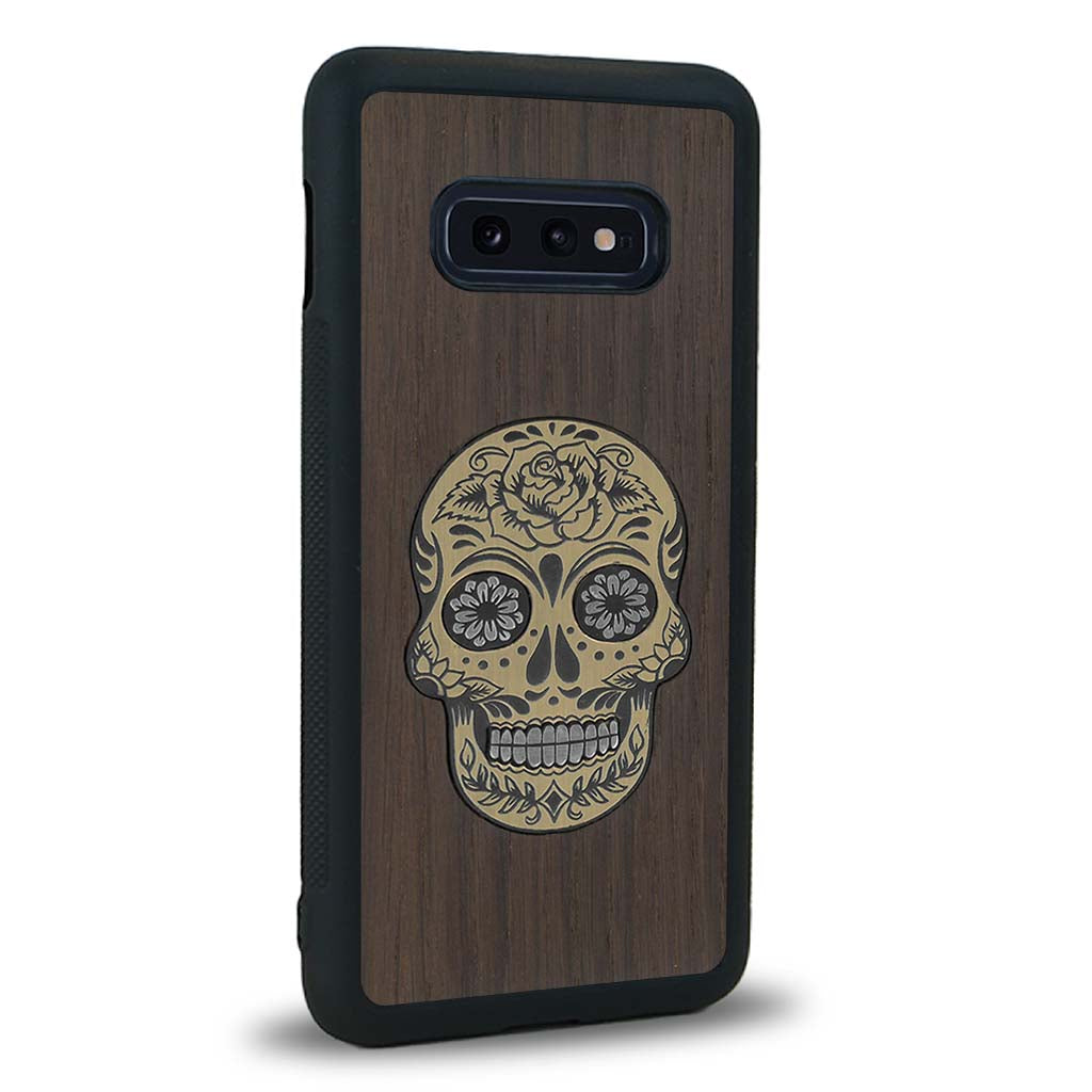 Coque de protection en bois véritable fabriquée en France pour Samsung S10E alliant du chêne fumé avec du métal argenté et doré représentant une tête de mort mexicaine sur le thème Dia de los Muertos