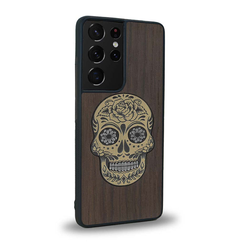 Coque de protection en bois véritable fabriquée en France pour Samsung S20 Ultra alliant du chêne fumé avec du métal argenté et doré représentant une tête de mort mexicaine sur le thème Dia de los Muertos