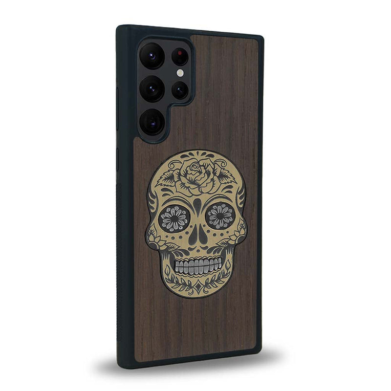 Coque de protection en bois véritable fabriquée en France pour Samsung S22 Ultra alliant du chêne fumé avec du métal argenté et doré représentant une tête de mort mexicaine sur le thème Dia de los Muertos