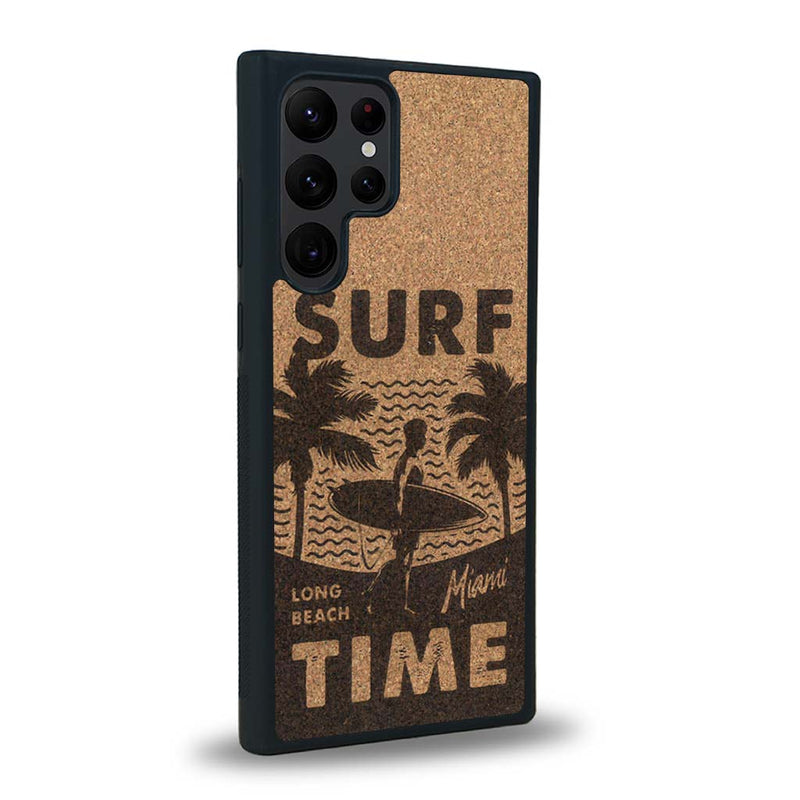 Coque de protection en bois véritable fabriquée en France pour Samsung S23 Ultra sur le thème chill avec un motif représentant une silouhette tenant une planche de surf sur une plage entouré de palmiers et les mots "Surf Time Long Beach Miami"