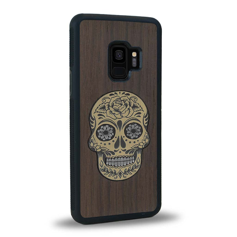 Coque de protection en bois véritable fabriquée en France pour Samsung S9 alliant du chêne fumé avec du métal argenté et doré représentant une tête de mort mexicaine sur le thème Dia de los Muertos