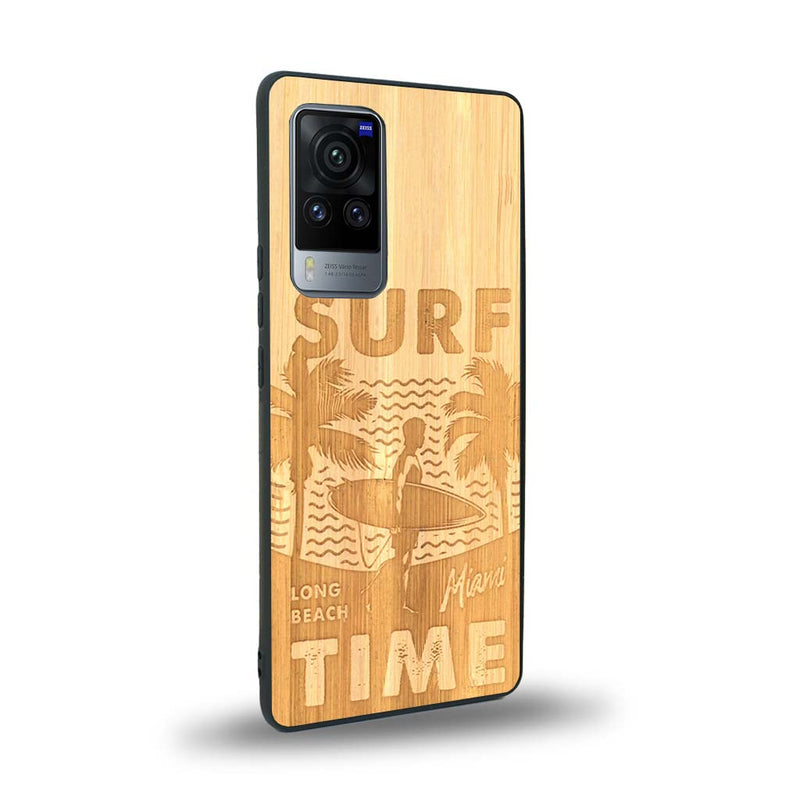 Coque de protection en bois véritable fabriquée en France pour Vivo X60 sur le thème chill avec un motif représentant une silouhette tenant une planche de surf sur une plage entouré de palmiers et les mots "Surf Time Long Beach Miami"