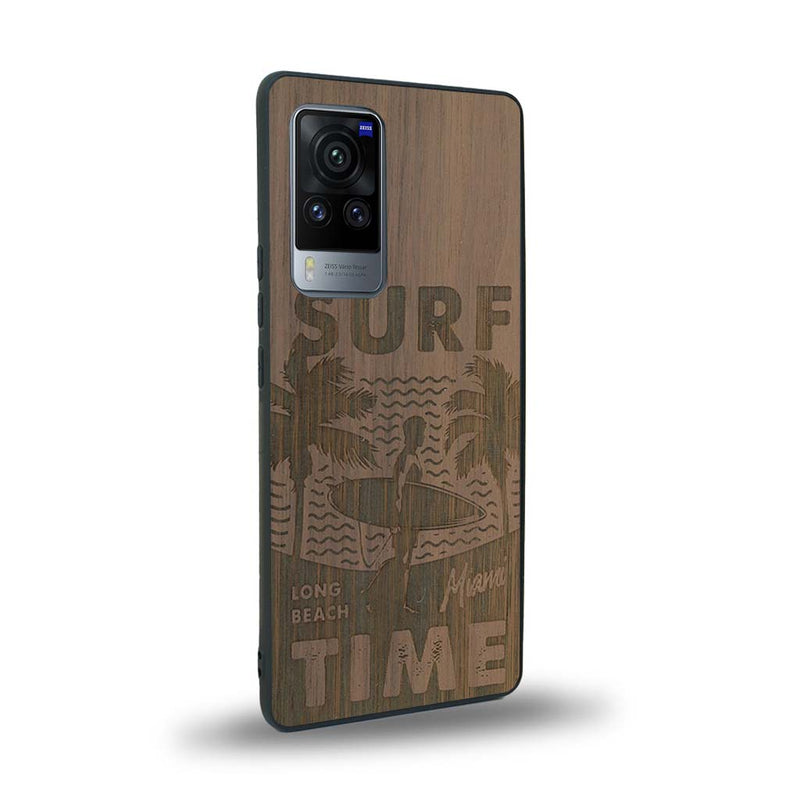 Coque de protection en bois véritable fabriquée en France pour Vivo X60 sur le thème chill avec un motif représentant une silouhette tenant une planche de surf sur une plage entouré de palmiers et les mots "Surf Time Long Beach Miami"