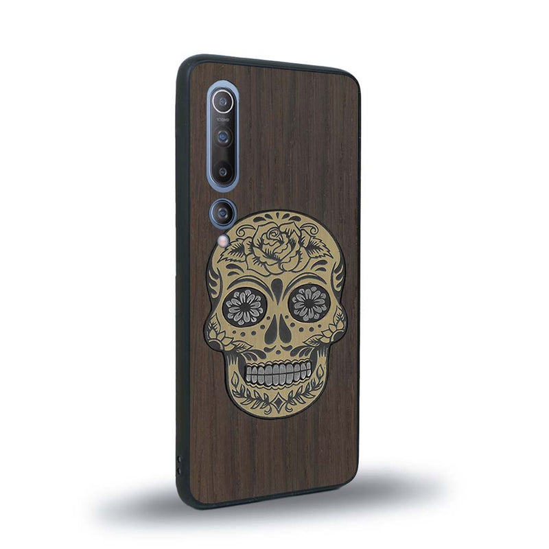 Coque de protection en bois véritable fabriquée en France pour Xiaomi Mi 10 alliant du chêne fumé avec du métal argenté et doré représentant une tête de mort mexicaine sur le thème Dia de los Muertos