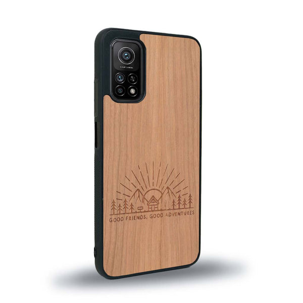 Coque de protection en bois véritable fabriquée en France pour Xiaomi Mi 10 Lite sur le thème chill et nature avec un motif représentant un levé de soleil sur un paysage de montagne avec des sapins et un chalet et la phrase "Good friends, good adventure"