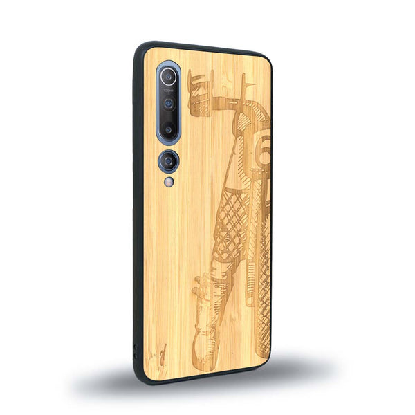 Coque de protection en bois véritable fabriquée en France pour Xiaomi Mi 10 représentant une vue de face d'une femme sur une moto vintage dessinée à la main par l'artiste Maud Dabs