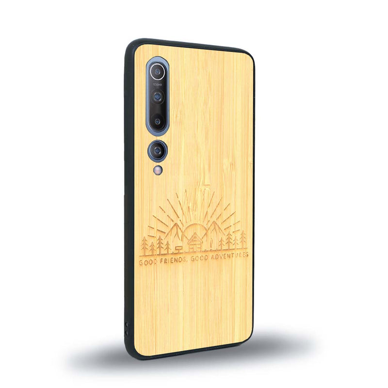 Coque de protection en bois véritable fabriquée en France pour Xiaomi Mi 10 sur le thème chill et nature avec un motif représentant un levé de soleil sur un paysage de montagne avec des sapins et un chalet et la phrase "Good friends, good adventure"