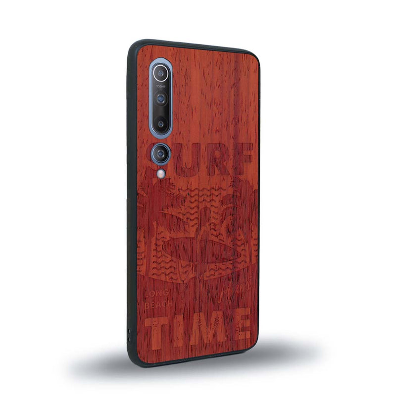 Coque de protection en bois véritable fabriquée en France pour Xiaomi Mi 10 sur le thème chill avec un motif représentant une silouhette tenant une planche de surf sur une plage entouré de palmiers et les mots "Surf Time Long Beach Miami"