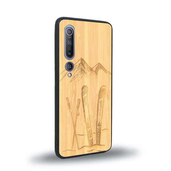 Coque de protection en bois véritable fabriquée en France pour Xiaomi Mi 10 sur le thème de la montagne, du ski et de la neige avec un motif représentant une paire de ski plantée dans la neige avec en fond des montagnes enneigées