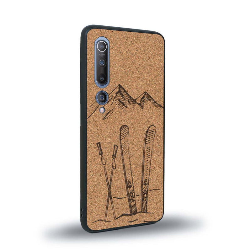 Coque de protection en bois véritable fabriquée en France pour Xiaomi Mi 10 sur le thème de la montagne, du ski et de la neige avec un motif représentant une paire de ski plantée dans la neige avec en fond des montagnes enneigées