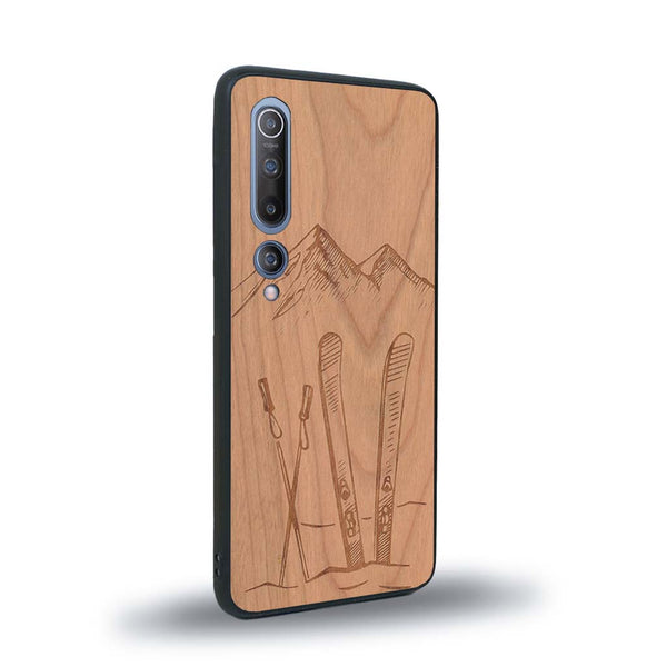 Coque de protection en bois véritable fabriquée en France pour Xiaomi Mi 10 sur le thème de la montagne, du ski et de la neige avec un motif représentant une paire de ski plantée dans la neige avec en fond des montagnes enneigées