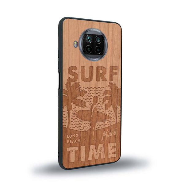 Coque de protection en bois véritable fabriquée en France pour Xiaomi Mi 10T Lite sur le thème chill avec un motif représentant une silouhette tenant une planche de surf sur une plage entouré de palmiers et les mots "Surf Time Long Beach Miami"