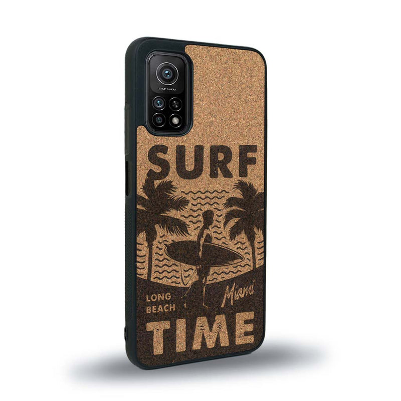 Coque de protection en bois véritable fabriquée en France pour Xiaomi Mi 10T Pro sur le thème chill avec un motif représentant une silouhette tenant une planche de surf sur une plage entouré de palmiers et les mots "Surf Time Long Beach Miami"