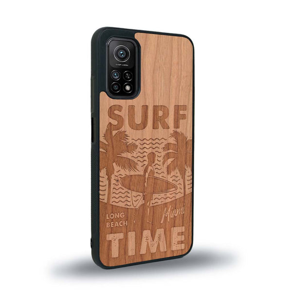 Coque de protection en bois véritable fabriquée en France pour Xiaomi Mi 10T Pro sur le thème chill avec un motif représentant une silouhette tenant une planche de surf sur une plage entouré de palmiers et les mots "Surf Time Long Beach Miami"
